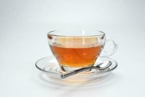 klar slicka te i en transparent glas kopp fat sked på vit bakgrund foto