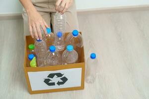 volontär- ha kvar plast flaska in i papper låda på Hem eller kontor. hand sortering återvinna sopor. ekologi, miljö, förorening, kassera återvinning, avfall förvaltning och skräp separation begrepp foto
