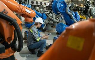 en kvinna ingenjör installerar en program på en robotik ärm i en robot lager. och testa de drift innan sändning de maskin till de kund. foto