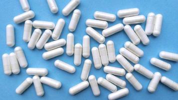 vita piller kapslar på blå bakgrund enkla platt låg med pastell textur medicinska koncept stock foto