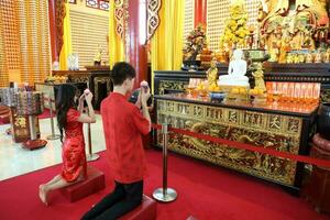 ung söder öst asiatisk kinesisk man kvinna traditionell kostym kinesisk ny år hälsning utomhus på tempel foto