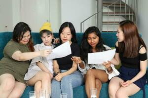 ung asiatisk kvinna grupp prata skvaller chatt sjunga läsa diskutera ansikten uttryck på blå levande rum soffa foto