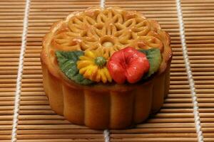 färgrik blomma dekorerad cake kinesisk mitten höst festival på bambu mat matta bakgrund foto