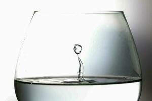 vatten liten droppe släppa stänk kollision droppande pelare reflexion i brandy glas refraktion foto