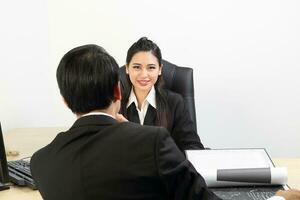 ung asiatisk manlig kvinna bär kostym Sammanträde på kontor skrivbord se på kamera över de axel foto