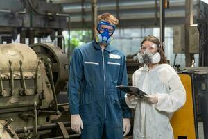 nödsituation förorening fabrik begrepp. porträtt ingenjör bär en mekanisk overall och gas mask ser på de kamera med hans vapen korsade. foto