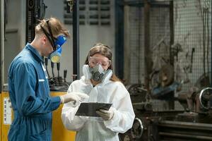 nödsituation förorening fabrik begrepp. de ingenjör, bär en mekaniker overall och ppe och gas mask, utseende på de kamera med hans vapen korsade. foto