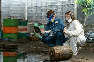 nödsituation förorening fabrik begrepp. ingenjörer bär mekaniker jumpsuits och ppe och gas masker inspektera olja på de fabrik golv. foto