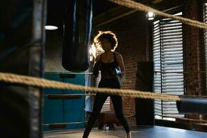 kvinnor själv försvar flicka kraft. afrikansk amerikan kvinna kämpe Träning slag på boxning ringa. friska stark flicka stansning boxning väska. Träning dag i boxning Gym. styrka passa kropp träna Träning. foto