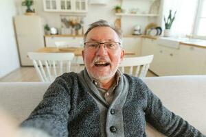 Lycklig mitten åldrig senior man prata på video ring upp med vänner familj. skrattande mogna gammal senior farfar har roligt tala med vuxen upp barn uppkopplad. huvudskott porträtt selfie webbkamera se. foto