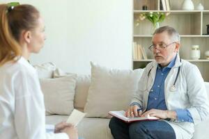 senior man läkare granskning yound kvinna i läkare kontor eller på Hem. flicka patient och läkare ha samråd i sjukhus rum. medicin sjukvård medicinsk kolla upp. besök till läkare. foto