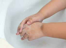 barn tvätta deras händer med hand tvål till förhindra infektion och virus foto