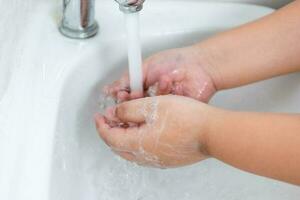 barn tvätta deras händer med hand tvål till förhindra infektion och virus foto