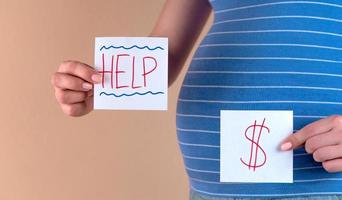 en närbild av magen på en gravid kvinna med orden hjälp och ett dollartecken