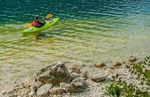 caucasian manlig Kajakpaddling i klar vattnen av sjö. foto