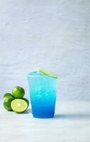 blå hawaiian dryck i en plast glas och kalk på vit bakgrund foto