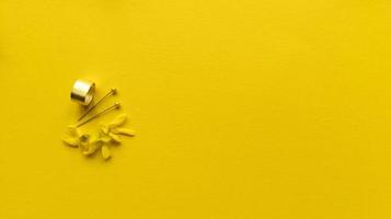 fingerborg nålar med huvud och blommor forsythia maluch på gul bakgrund monokrom enkel platt låg med pastell konsistens mode eco koncept Stockfoto