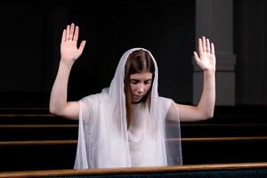 en ung blygsam tjej med en näsduk på huvudet sitter i kyrkan och ber foto