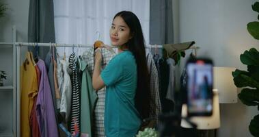 ung asiatisk kvinna mode designer använder sig av mobil telefon leva ångande foto