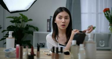 skön ung asiatisk kvinna bloggare visar på vilket sätt till göra upp och använda sig av kosmetika foto