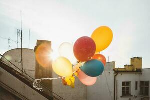 färgrik födelsedag ballonger, de dekorationer av tak fest med de Sol Bakom under de solnedgång foto