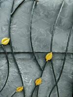abstrakt metall bakgrund med gul löv på en svart bakgrund. abstrakt bakgrund med löv på de järn staket. detalj av en smidda metall staket med gul löv på Det. foto