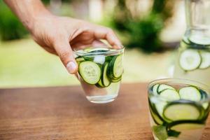 håller ett glas med infunderat detoxvatten foto