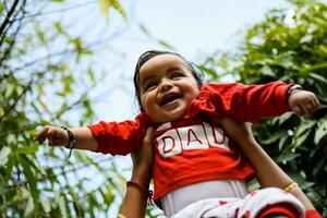 söt liten indisk spädbarn Sammanträde njuter utomhus- skjuta på samhälle parkera i delhi, söt bebis pojke Sammanträde på färgrik matta med gräs runt om, bebis pojke utomhus- skjuta foto