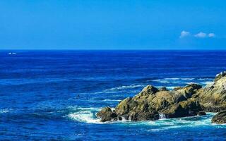 surfare vågor turkos blå vatten stenar klippor stenblock puerto escondido. foto