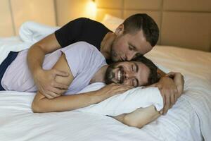 Gay par fattande varje Övrig med deras ögon stängd. två ung manlig älskande rörande deras ansikten tillsammans medan liggande i säng i de morgon. öm ung Gay par bindning på Hem. foto