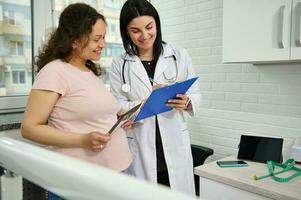 läkare gynekolog obstetriker hört en gravid patient handla om de bebis ultraljud skanna i gynekologisk klinik. foto