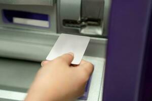 stänga upp av kvinna hand använder sig av kreditera till bortdragande pengar från Bankomat maskin. foto