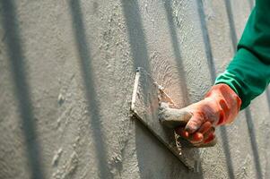 närbild hand av arbetare gips cement på väggen för att bygga hus foto