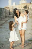 mor och henne döttrar klädd i vit gående längs cartagena vägg foto