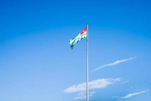 Abkaziens flagga på bakgrunden av blå himmel och moln foto