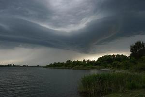 dramatiskt landskap med stormmoln över sjön foto