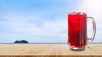 färsk roselle juice ljuv vatten och iced i glas på trä- tabell med strand landskap natur bakgrund, sommar hälsa drycker med is foto