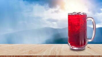 färsk roselle juice ljuv vatten och iced i glas på trä- tabell med natur bakgrund, sommar hälsa drycker med is, röd juice med is kuber i glas foto