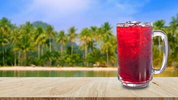 färsk roselle juice ljuv vatten och iced i glas på trä- tabell med strand landskap natur bakgrund, sommar hälsa drycker med is foto