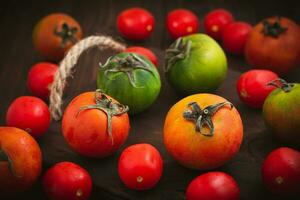 samling av hela färgad tomater eras på en trä- bakgrund, tomater fortfarande liv foto