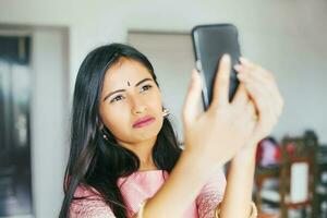 ung skön indisk kvinna bär traditionell tar en selfie foto