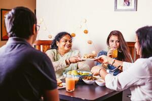 Lycklig indisk familj äter festlig middag tillsammans foto