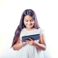 söt indisk liten flicka använder sig av läsplatta dator på henne studio porträtt på vit bakgrund foto