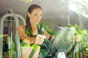 kvinna använder sig av elliptisk motionär i Gym foto