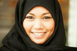 leende ung kvinna bär kohl och hijab foto