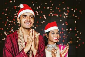 indisk par klädd i traditionell kläder fira jul och ny år förbi sång och bär jul hatt foto