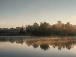 skön morgon- landskap med dimma över de sjö foto