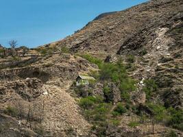 etnisk hus med trädgård på de kant av de avgrund på en berg topp på hög höjd över havet. en svår liv i en djup berg klyfta. dagestan. foto