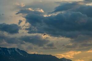 färgrik motor paraglider mot en molnig kväll himmel. de begrepp av skärmflygning, extrem sporter. skärmflygare, flygande vinge på solnedgång. foto