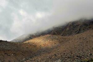 bergen i en tät dimma. mystisk landskap med skön skarp stenar i låg moln. skön berg dimmig landskap på avgrund kant med skarp stenar. foto